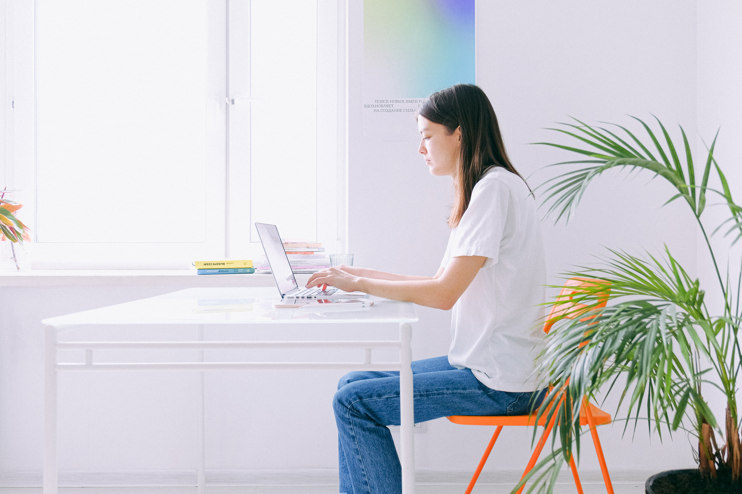 Woman In White Shirt And Blue Denim Jeans Sitting On Chair Using Laptop Computer